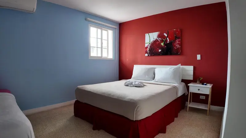 Une chambre lumineuse avec un lit double et une décoration murale colorée.