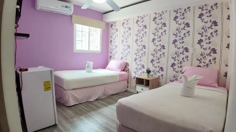 Une chambre avec deux lits simples et un petit réfrigérateur.