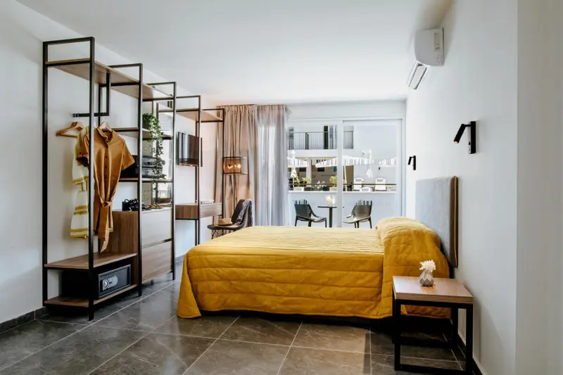 Une chambre lumineuse avec un lit jaune et un espace ouvert avec un portant à vêtements.