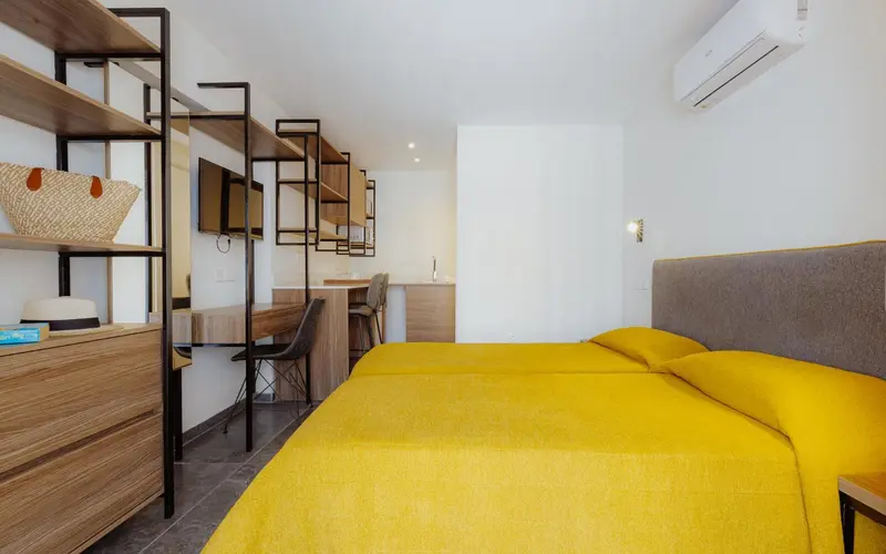 Chambre lumineuse avec un lit jaune et un espace bureau.