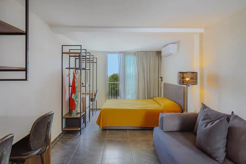 Une chambre lumineuse avec un lit jaune et un coin salon.