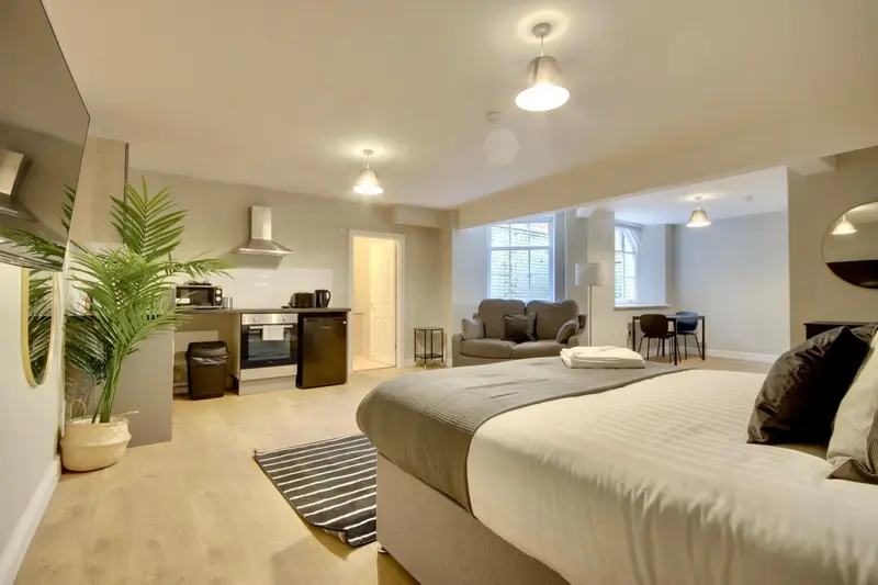 Espace de vie lumineux avec un lit, un canapé et une kitchenette.