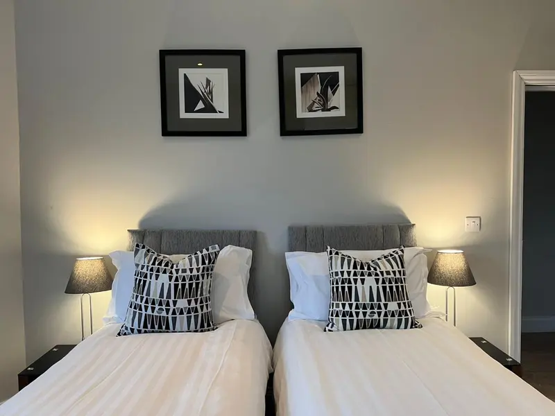 Deux lits simples avec oreillers et lampes de chevet dans une chambre.