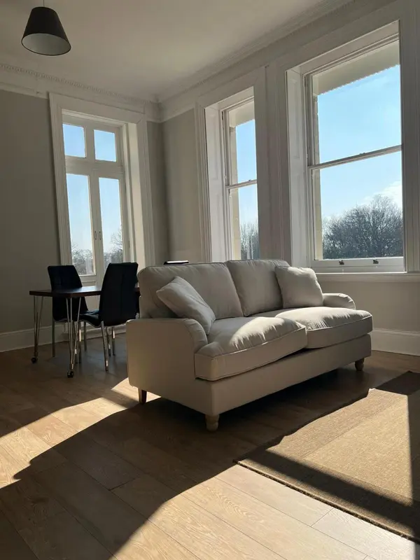 Un salon lumineux avec un canapé et une table basse près d'une fenêtre.