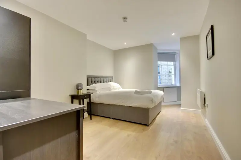 Une chambre lumineuse avec un lit double et un bureau.