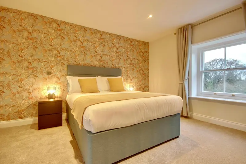 Une chambre lumineuse avec un lit double et un mur décoré.