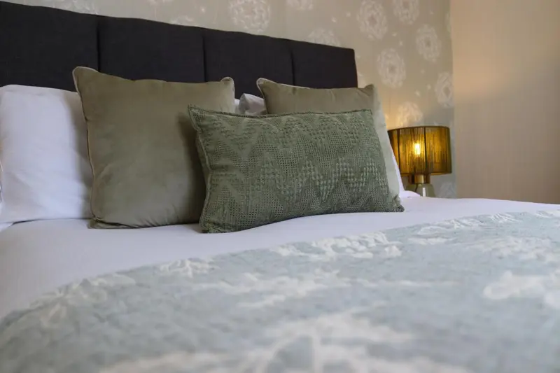 Un lit avec des oreillers et une couverture décorative.