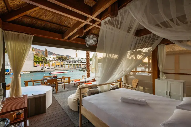Espace de détente extérieur avec lit à baldaquin et vue sur la mer.