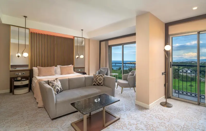 Espace de vie lumineux avec canapé, table basse et accès à un balcon offrant une vue sur la mer.