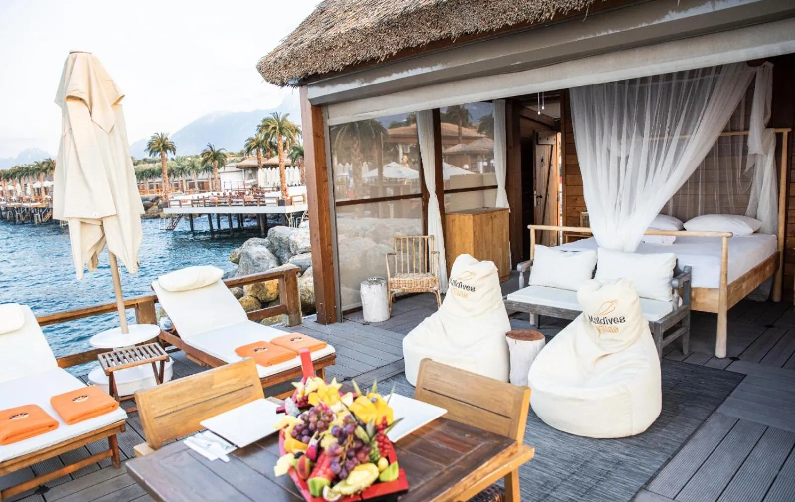 Terrasse en bois avec mobilier de détente et vue sur la mer.