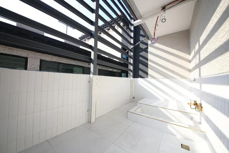 Espace extérieur lumineux avec murs blancs et structure ombragée.