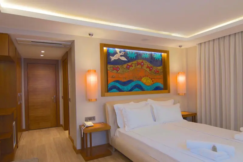 Une chambre lumineuse avec un grand lit et une décoration murale colorée.
