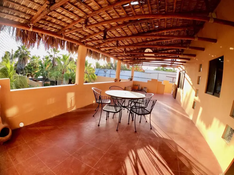 Terrasse ombragée avec table et chaises.