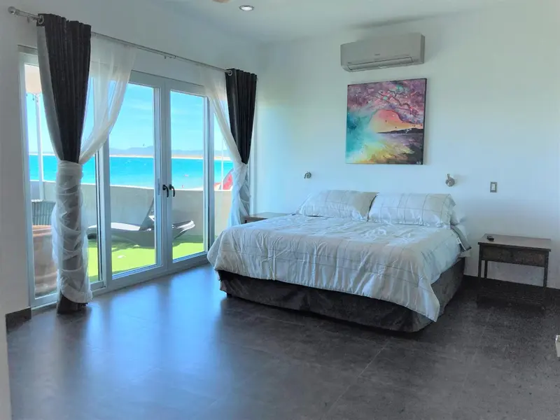 Une chambre lumineuse avec un grand lit donnant sur une vue mer.