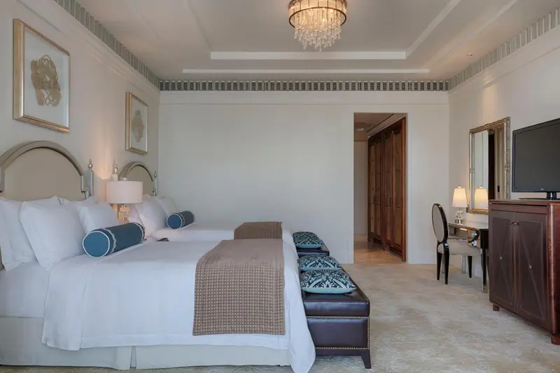Une chambre lumineuse avec deux lits et un coin bureau.