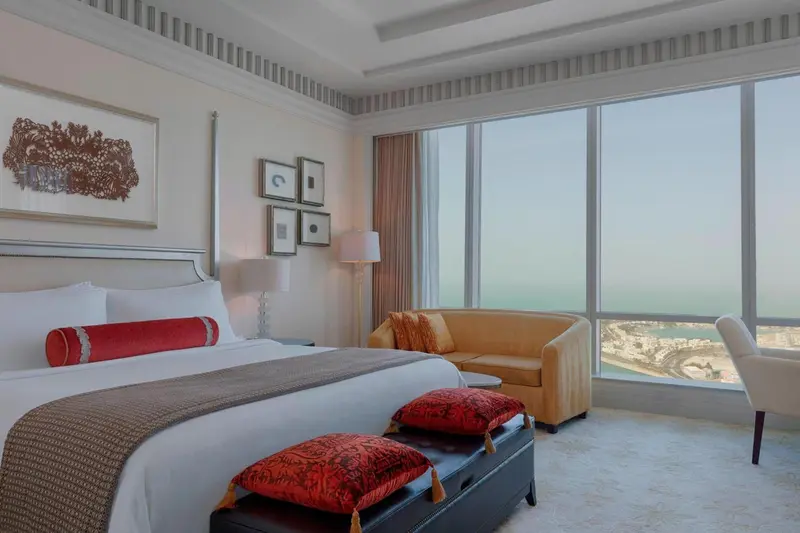 Chambre lumineuse avec un grand lit et un canapé face à la mer.