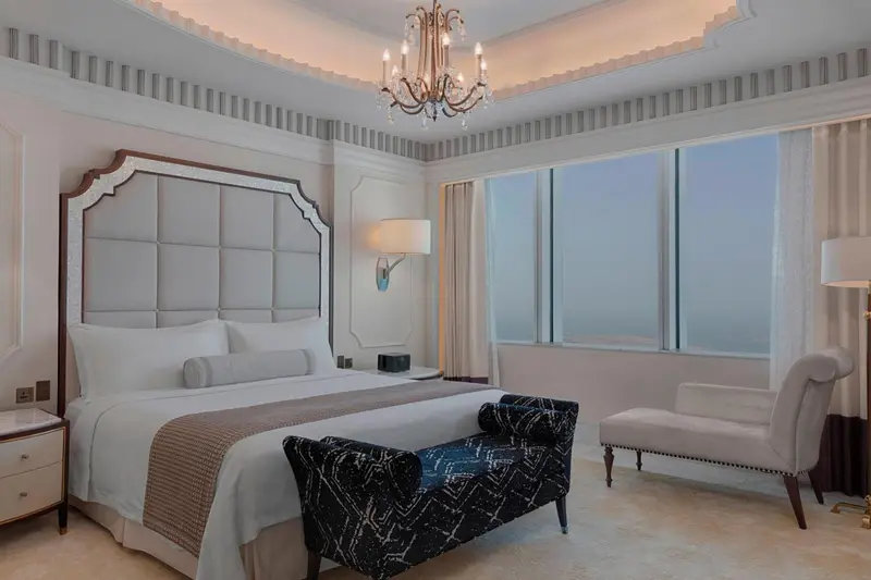 Une chambre lumineuse avec un grand lit et un fauteuil.