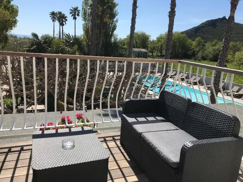 Terrasse aménagée avec salon et vue sur une piscine et la végétation.