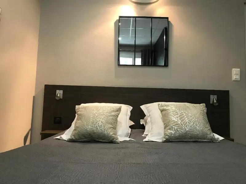 Un lit double avec des oreillers décoratifs dans une chambre sobre.