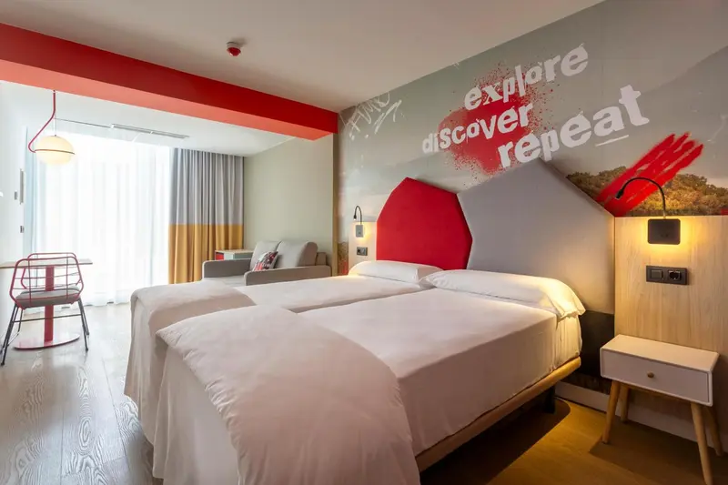 Une chambre lumineuse avec deux lits simples et un canapé.