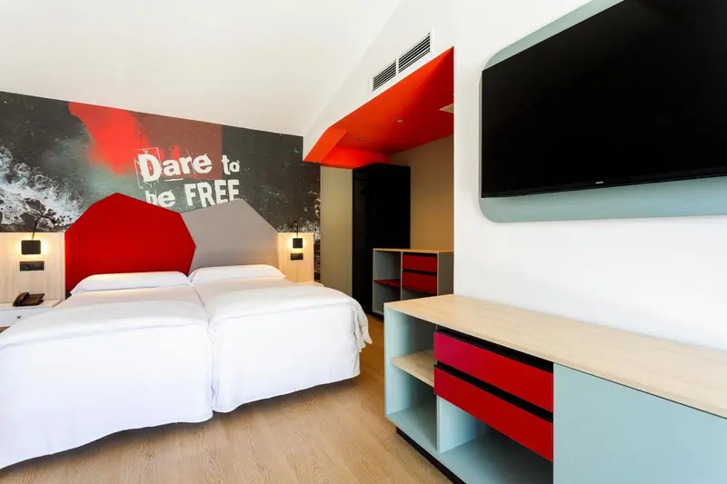 Une chambre lumineuse avec deux lits simples et un mur décoré.