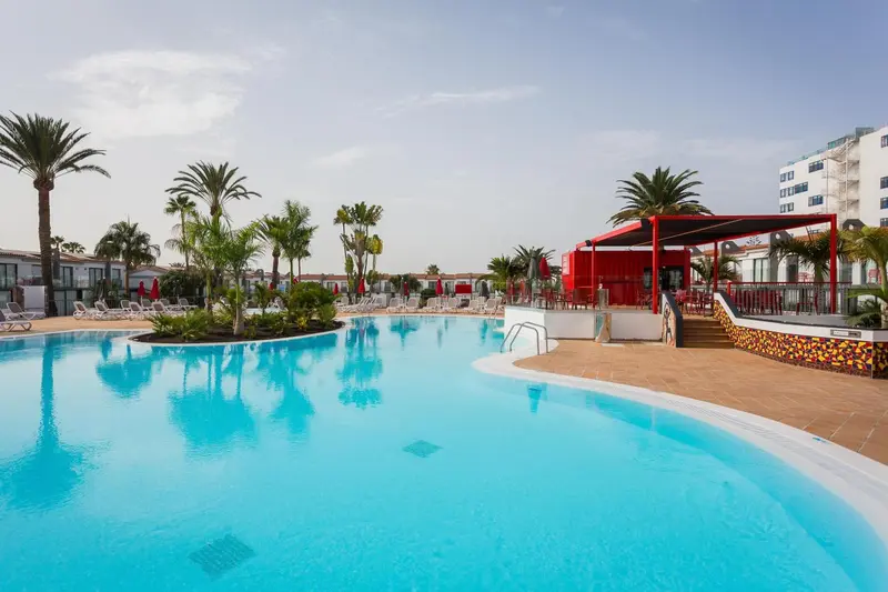 Une piscine rectangulaire avec une zone peu profonde et des transats.