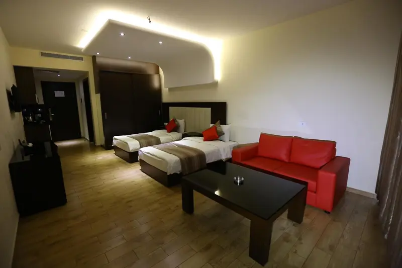 Une chambre lumineuse avec un canapé rouge et deux lits simples.