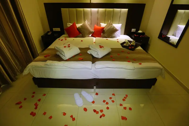 Lit double décoré de pétales de roses dans une chambre d'hôtel.