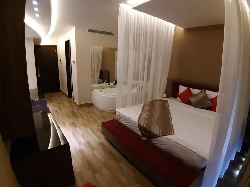 Une chambre spacieuse avec un lit à baldaquin et une baignoire à remous.