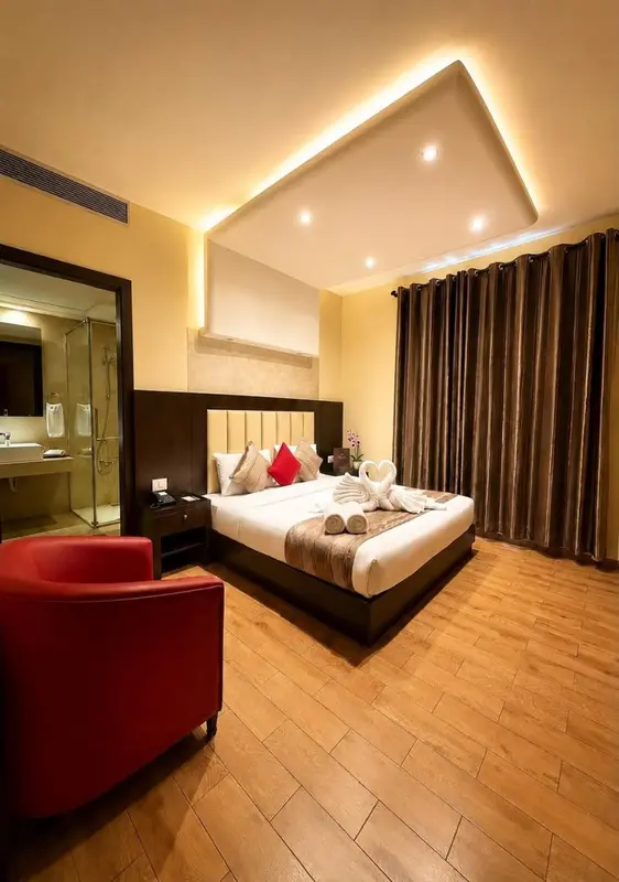 Une chambre lumineuse avec un grand lit et un fauteuil rouge.