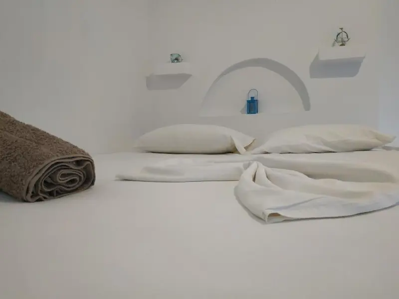 Un lit blanc avec des oreillers et une serviette roulée sur le côté.