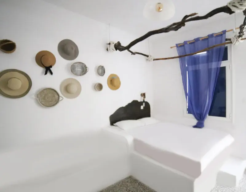 Une chambre lumineuse avec un lit blanc et une décoration murale originale de chapeaux.
