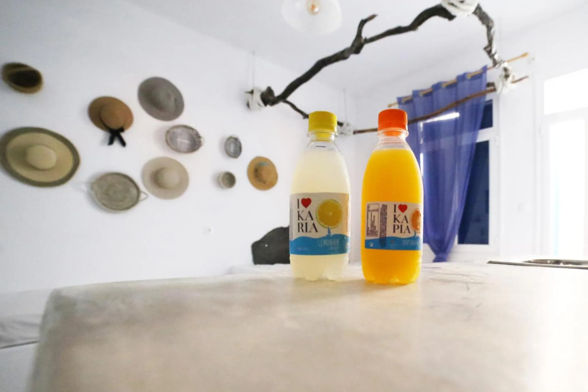 Des bouteilles de boissons sont posées sur une table contre un mur décoré de chapeaux.