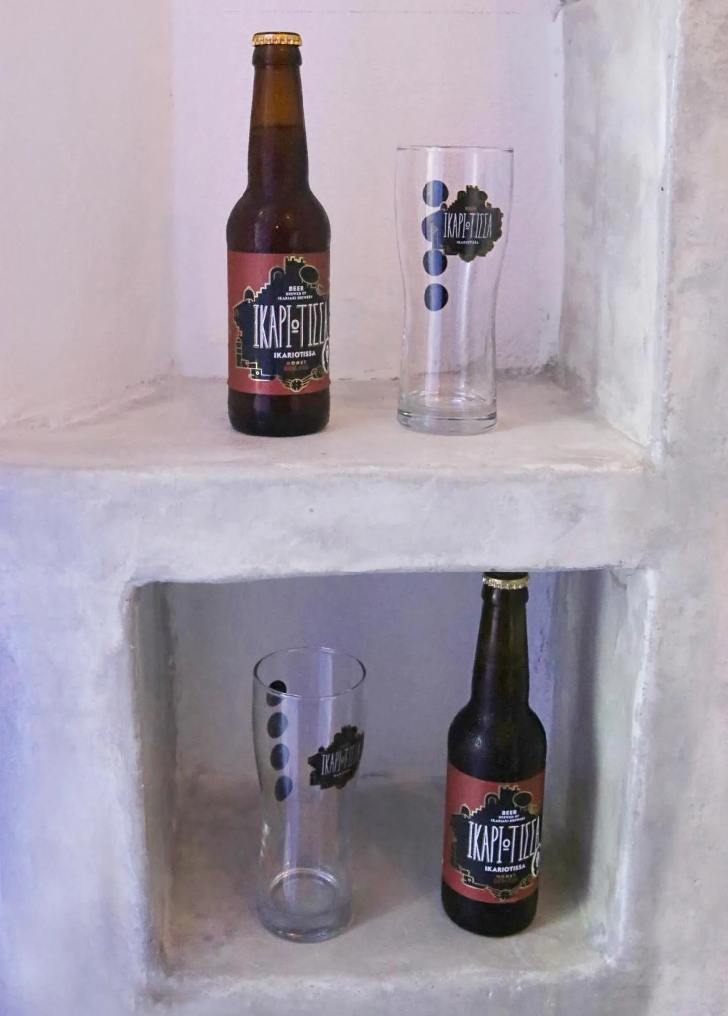 Deux bouteilles de bière et deux verres sur une étagère en pierre.