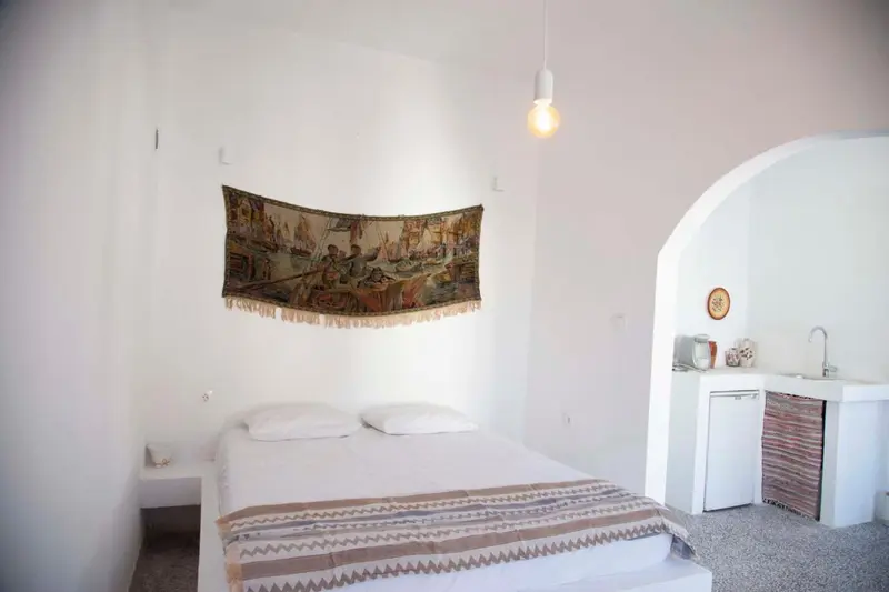 Une chambre lumineuse avec un lit et une kitchenette.