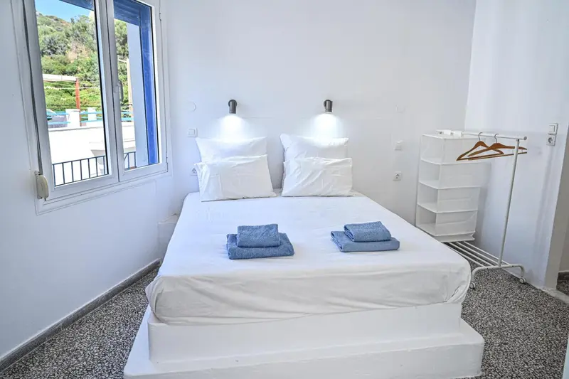 Une chambre lumineuse avec un grand lit recouvert de linge blanc.