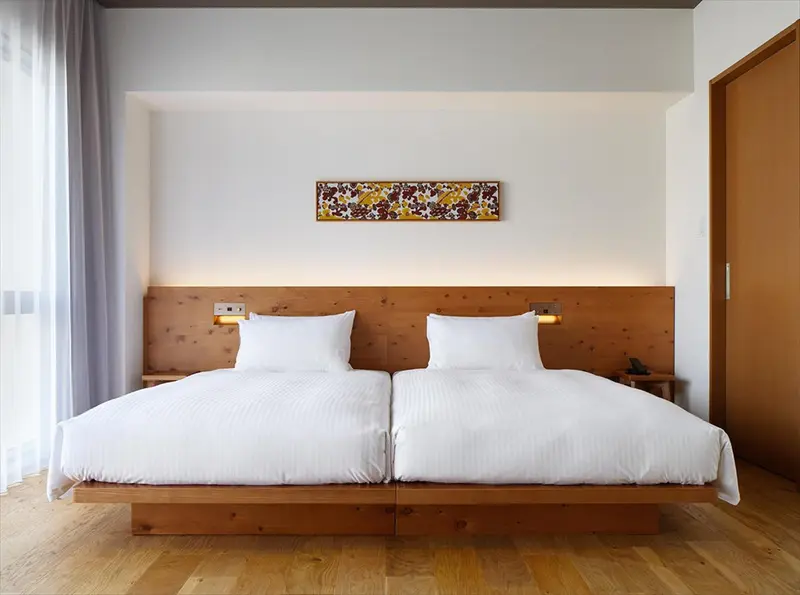 Une chambre lumineuse avec un grand lit double et une décoration murale.