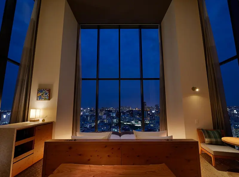 Une chambre lumineuse avec un grand lit et une vue sur la ville illuminée.