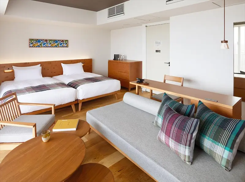 Une chambre lumineuse avec deux lits simples et un espace détente.