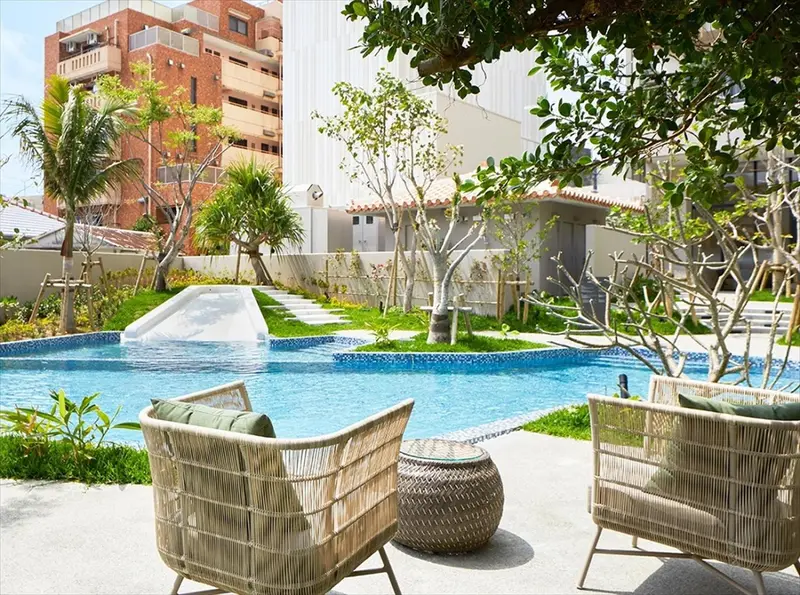 Deux fauteuils en rotin invitent à la détente au bord d'une piscine turquoise.