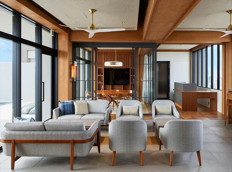 Espace de détente intérieur avec canapés et fauteuils près de grandes baies vitrées.