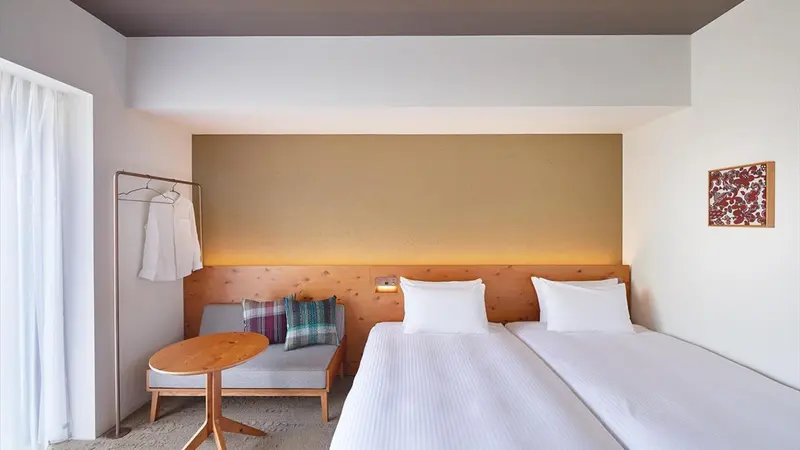 Une chambre lumineuse avec un lit double et un coin salon.