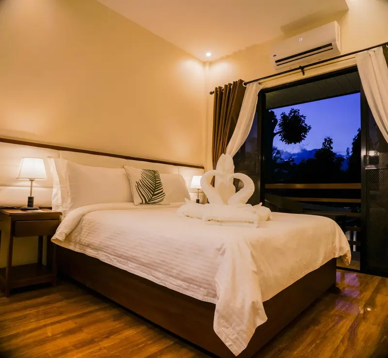 Une chambre lumineuse avec un grand lit et une vue sur la végétation.