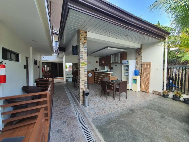 Terrasse ombragée avec mobilier de jardin et comptoir de bar.