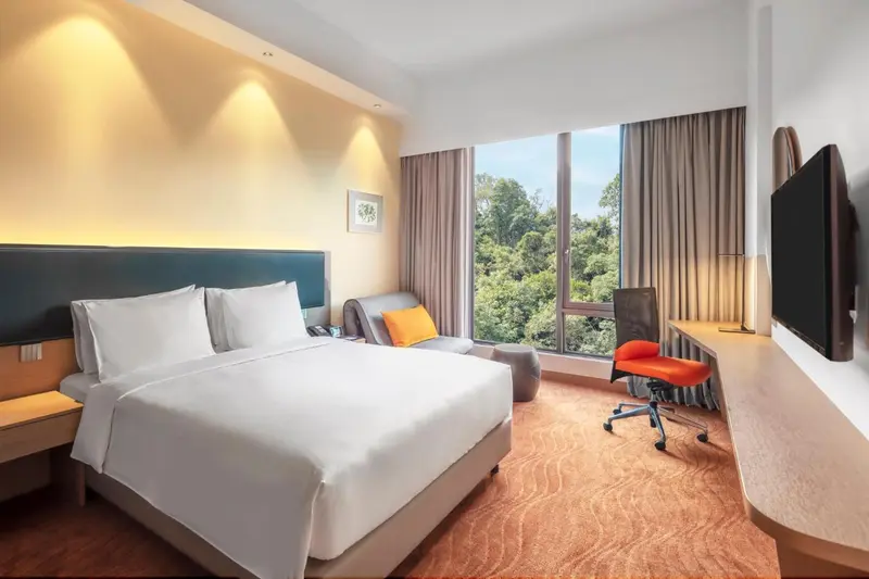 Chambre lumineuse avec un grand lit et un espace bureau.