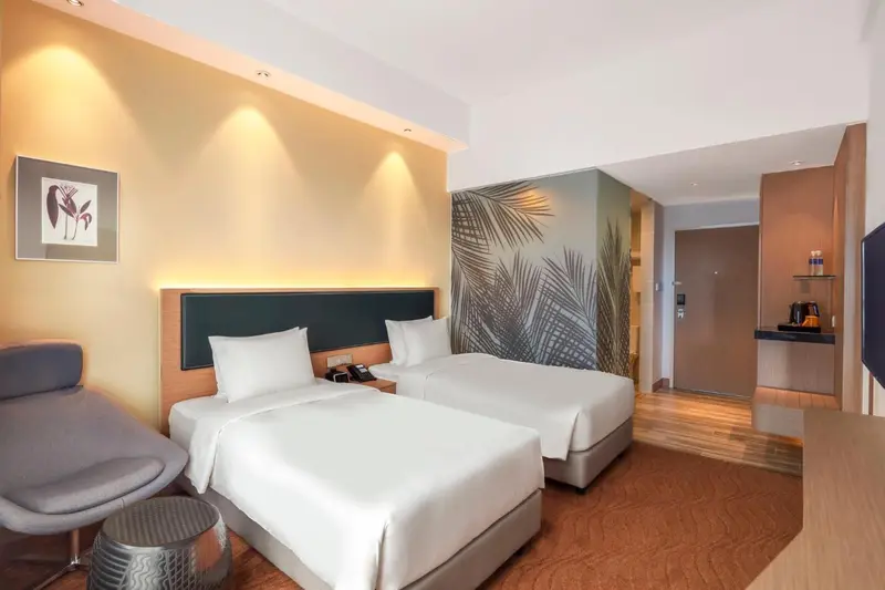 Chambre d'hôtel avec deux lits simples et un coin salon.