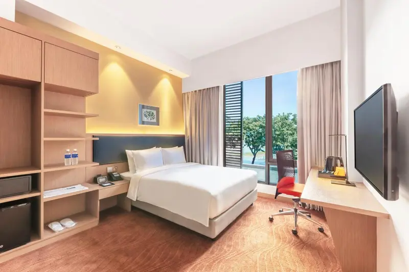 Chambre lumineuse avec un grand lit et un bureau près de la fenêtre.