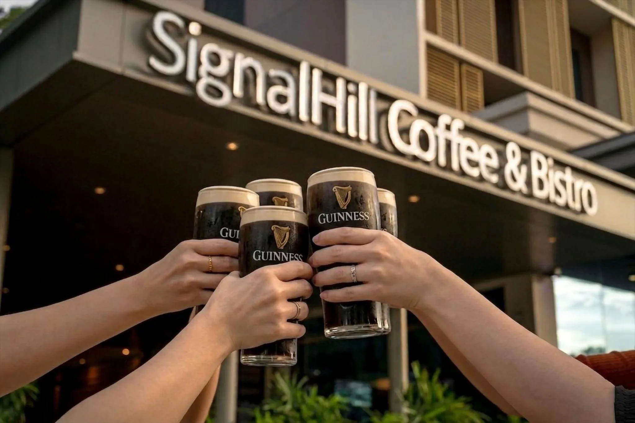 Des personnes trinquent avec des verres de bière devant un établissement.
