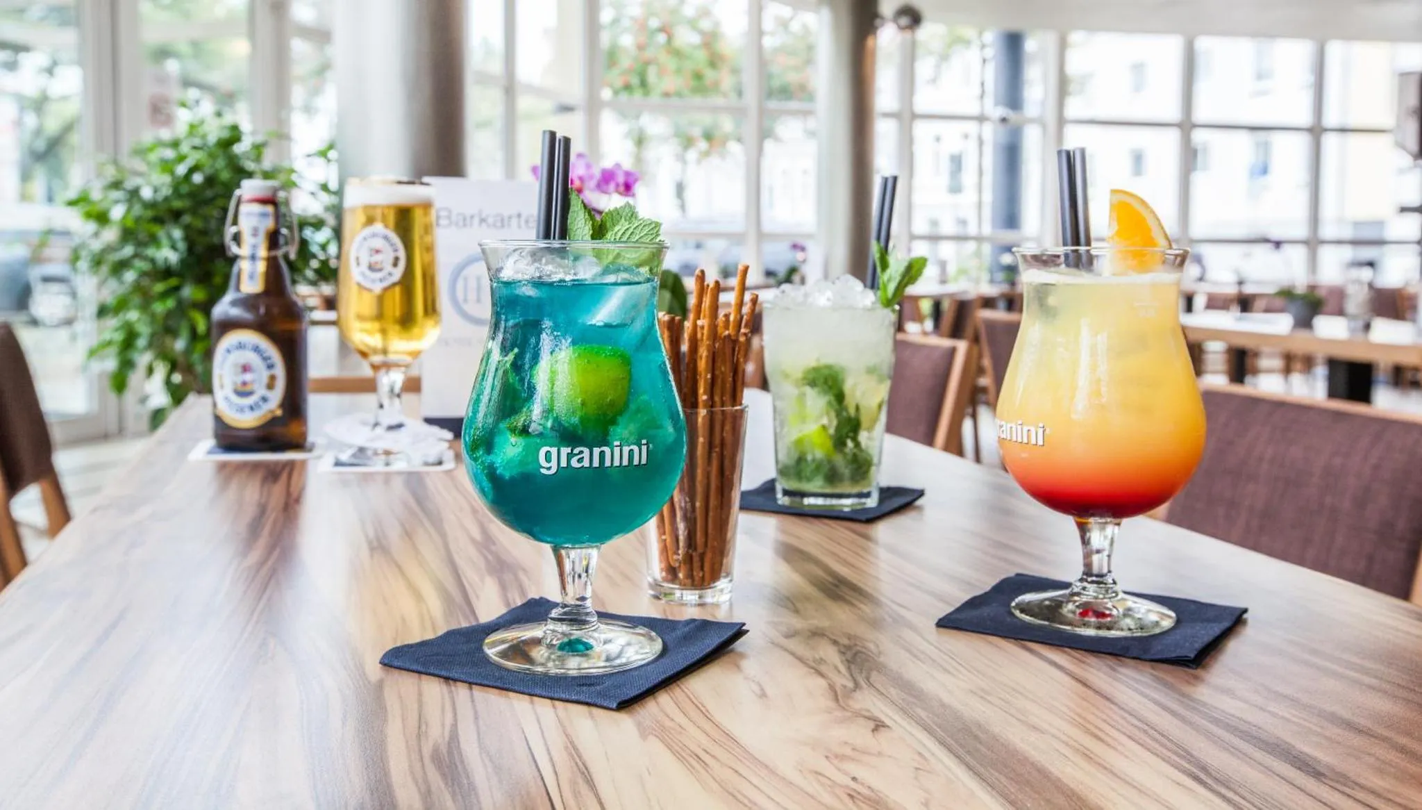 Des cocktails colorés sont servis sur une table en bois clair.