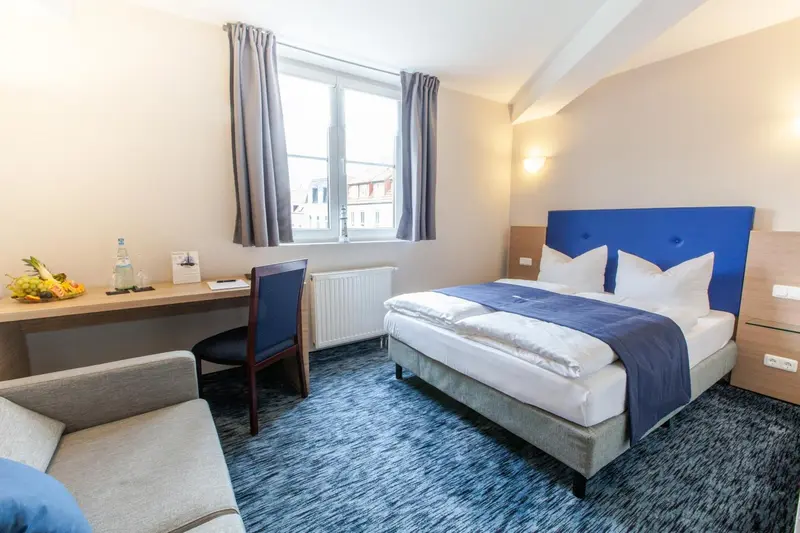 Une chambre d'hôtel lumineuse avec un lit double et un bureau.